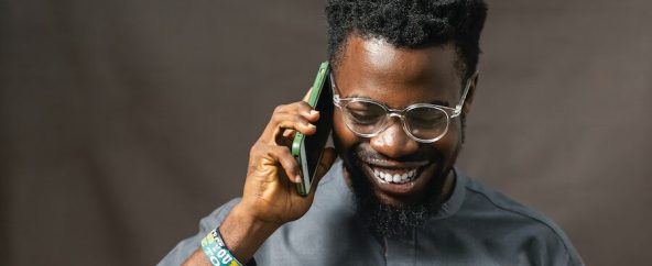 a man with a beard and glasses talking on a cell phone